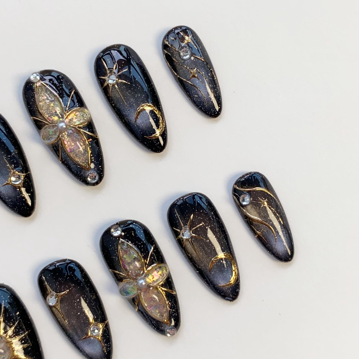 Black Cat Eye Nails With Gold Celestial Details and Gemstone Charms