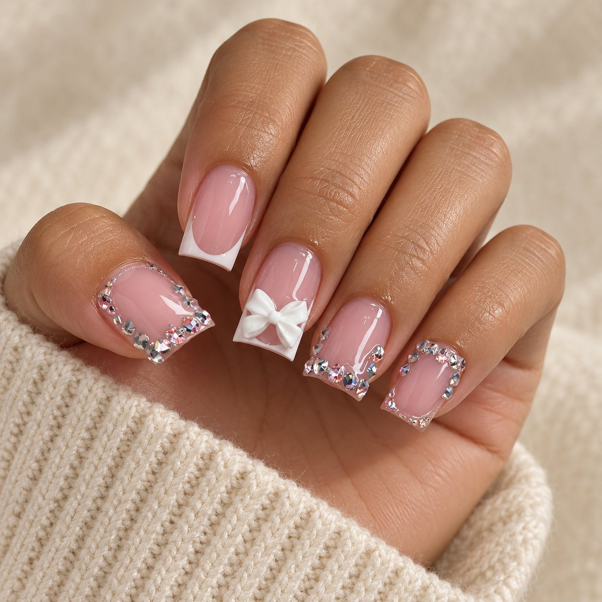 Blush Pink French Tip Nails With 3D White Bows and Rhinestones worn on hand