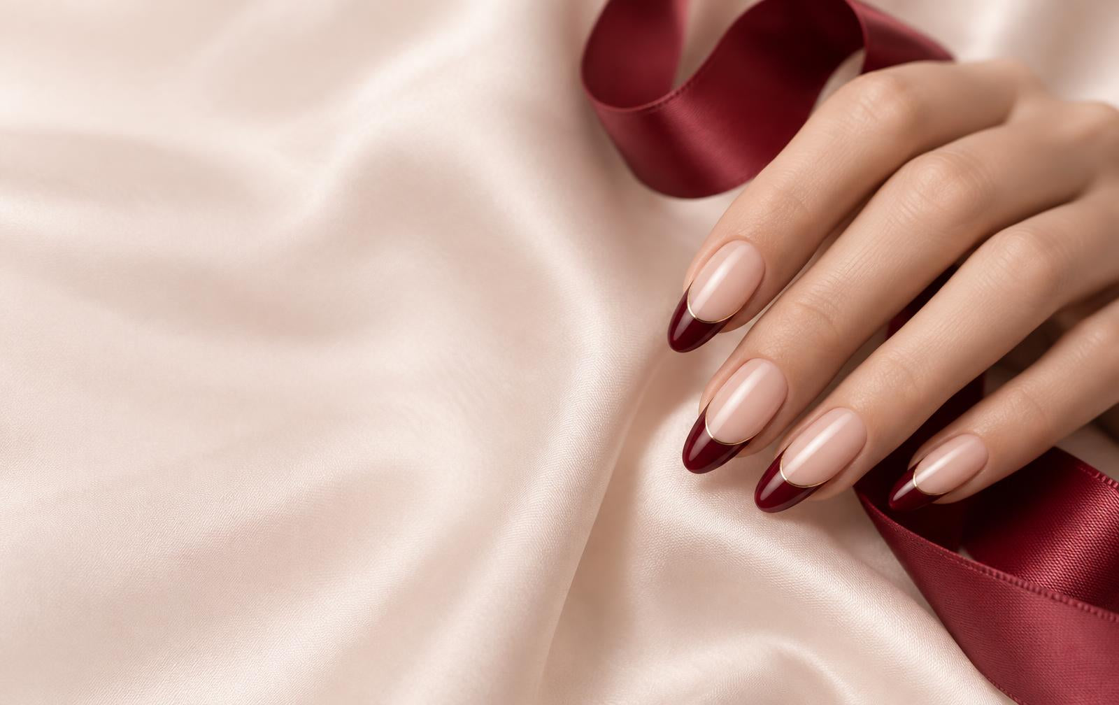 Handcrafted nude and burgundy French-tip almond nails on blush silk