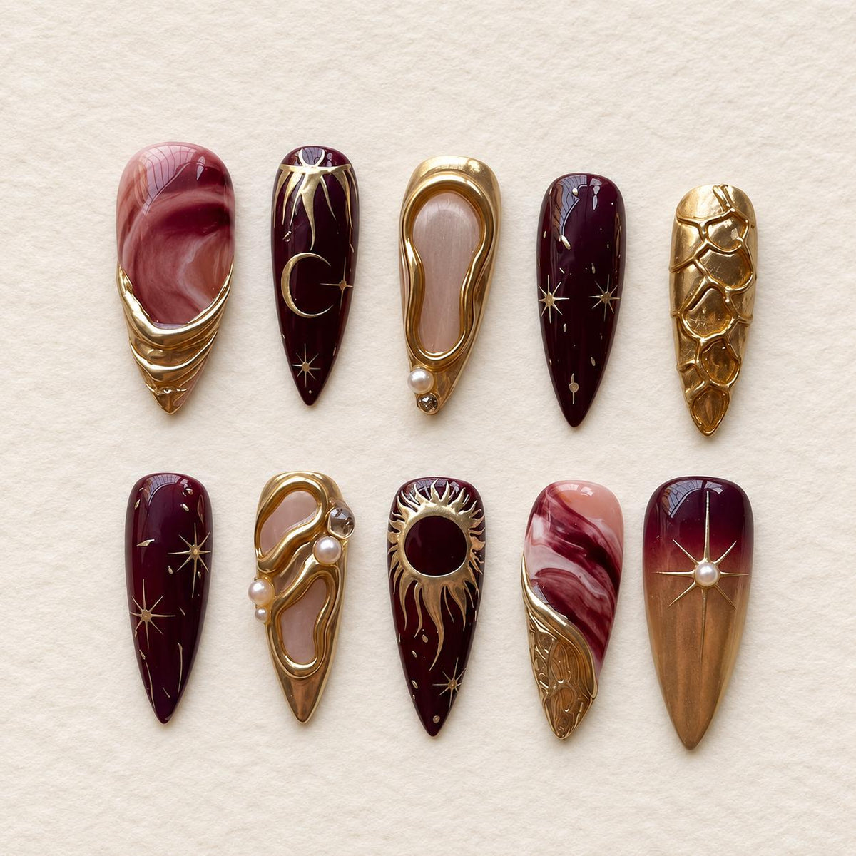 Burgundy and Rose Marble Celestial Nails with Gold Sun, Moon, and Pearl Details