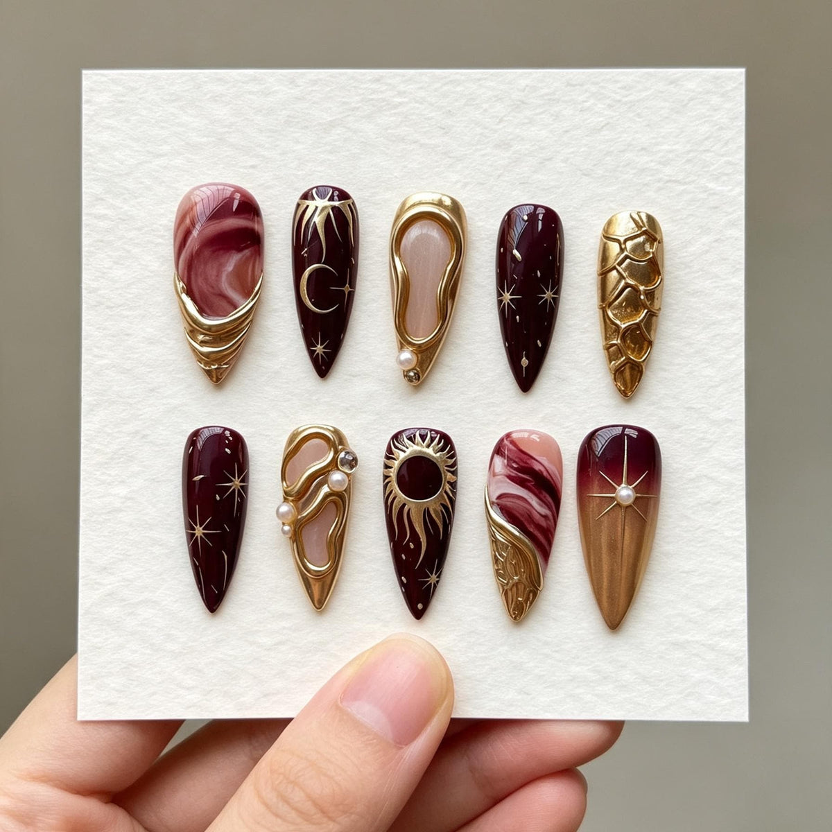 Burgundy and Rose Marble Celestial Nails with Gold Sun, Moon, and Pearl Details