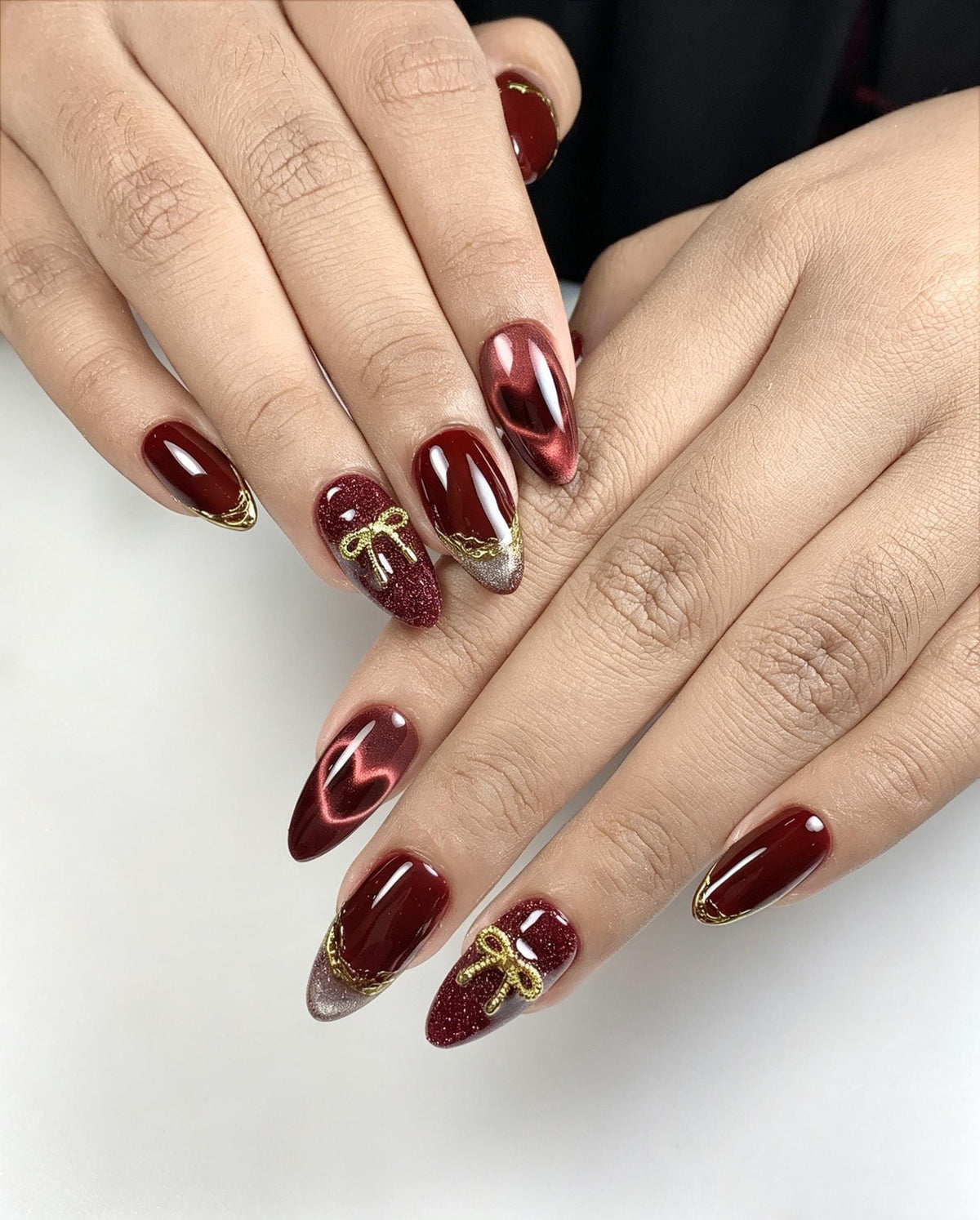 Burgundy Cat Eye Nails with Gold Bows, Glitter and Lace-Like Edging
