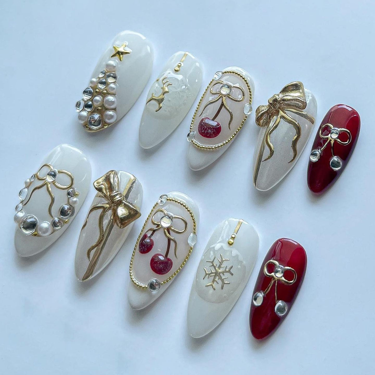 Milky White Christmas Nails With Pearl Trees, Gold Bows, Cherries, and Reindeer