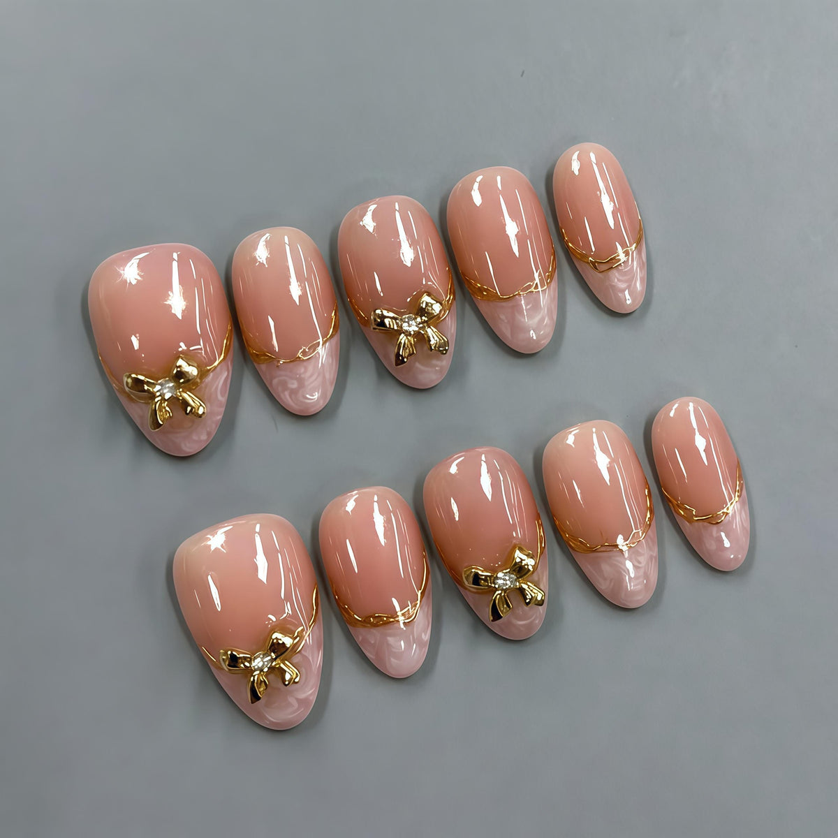 Nude Pink Marble Tip Nails with Gold Bows and Chain Details