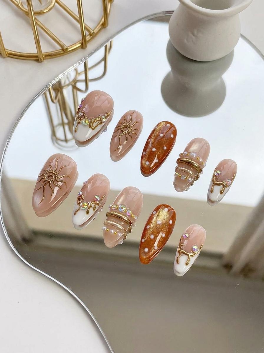 Blush French Tip Nails With Amber Dots, Gold Sun Motifs, and Rhinestones
