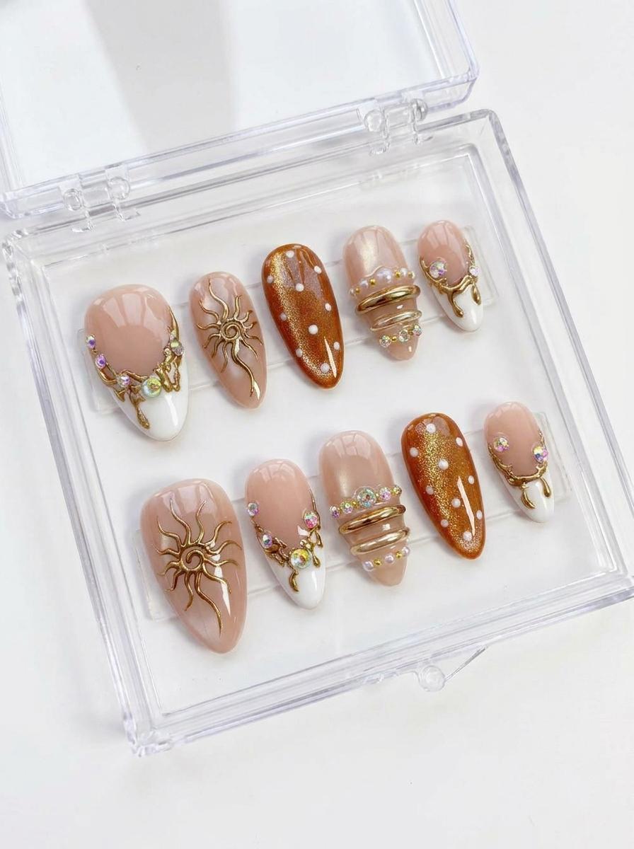Blush French Tip Nails With Amber Dots, Gold Sun Motifs, and Rhinestones