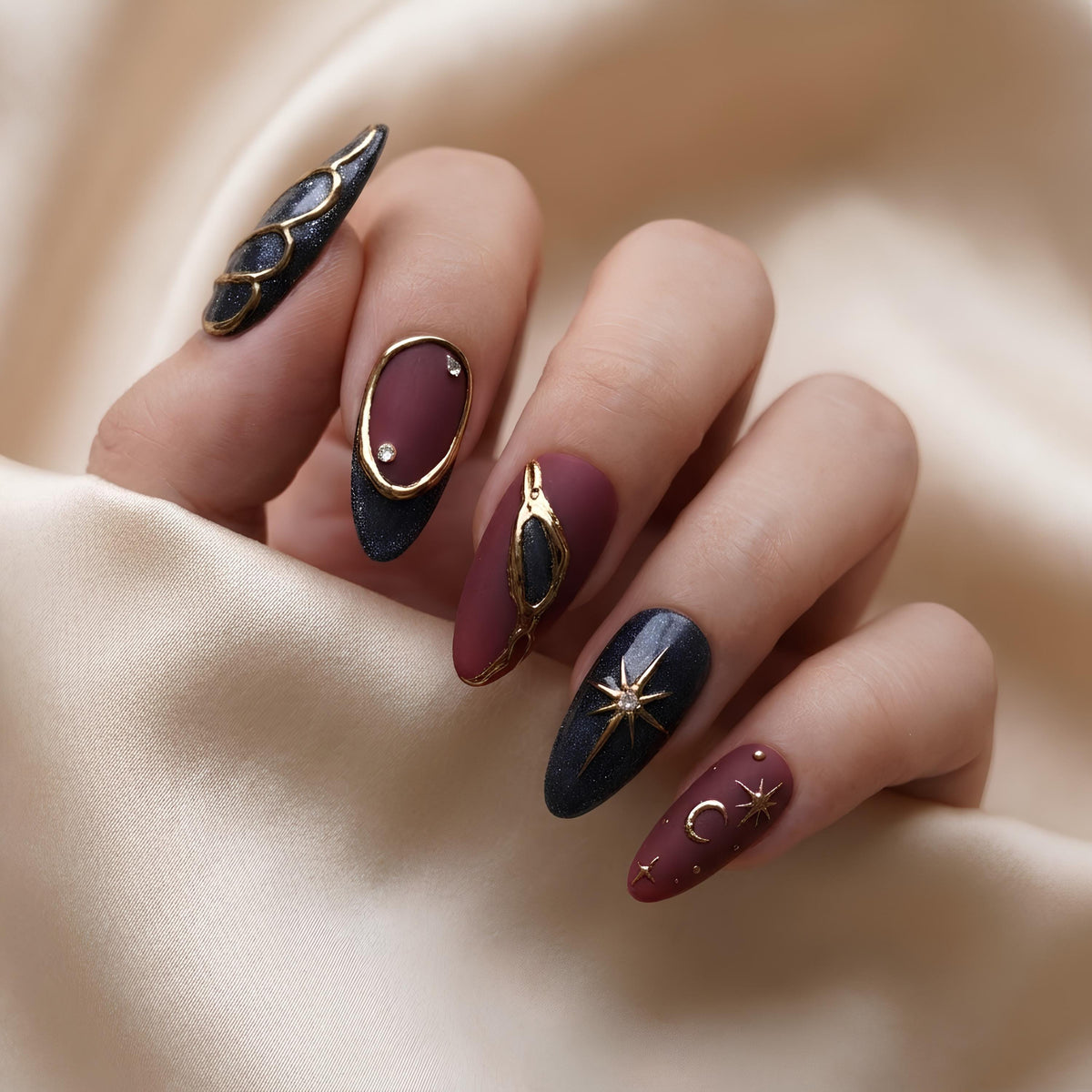 Burgundy and Black Celestial Nails with Gold Stars, Moons, and Rhinestone Accents