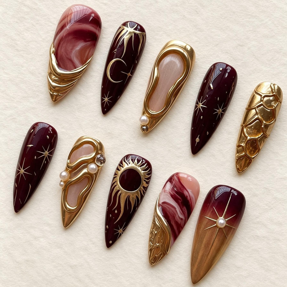 Burgundy and Rose Marble Celestial Nails with Gold Sun, Moon, and Pearl Details