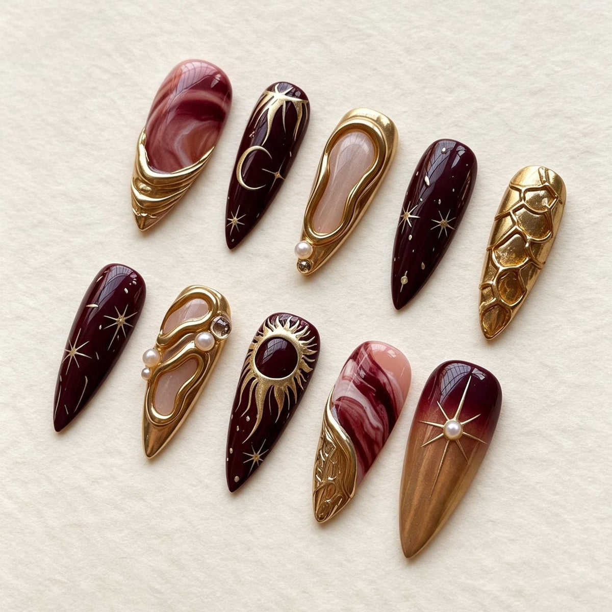 Burgundy and Rose Marble Celestial Nails with Gold Sun, Moon, and Pearl Details