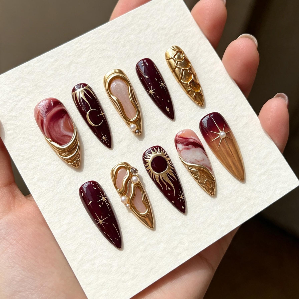 Burgundy and Rose Marble Celestial Nails with Gold Sun, Moon, and Pearl Details