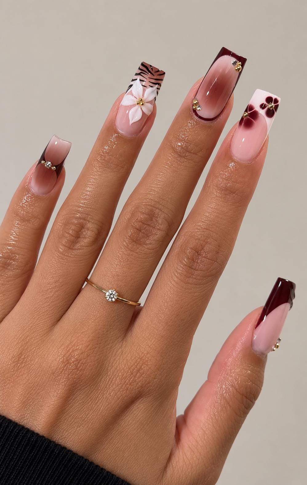 Burgundy French Tip Nails With Floral Details, Zebra Print, and Gold Accents