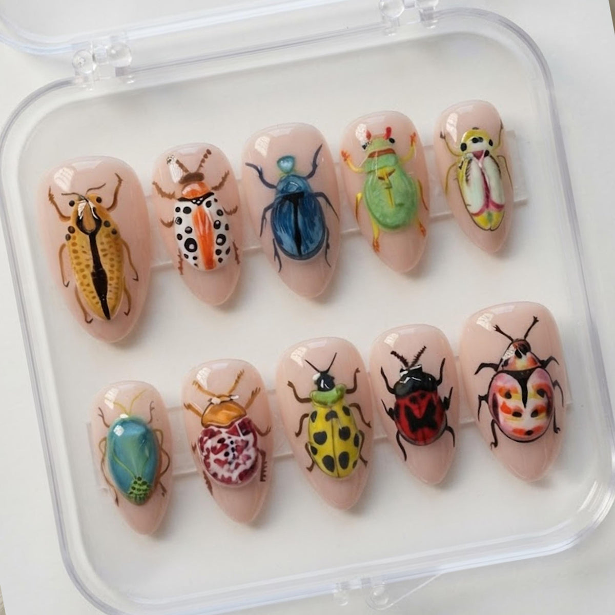 Colorful Beetle and Insect Press-On Nails on a Sheer Nude-Pink Base