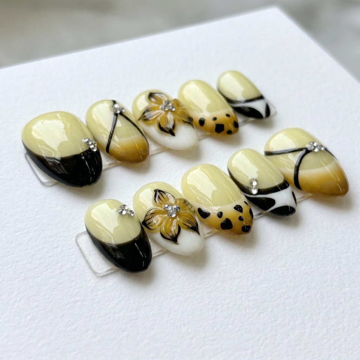 Cream and Black French Tip Nails with Floral Rhinestones and Spotted Amber Details