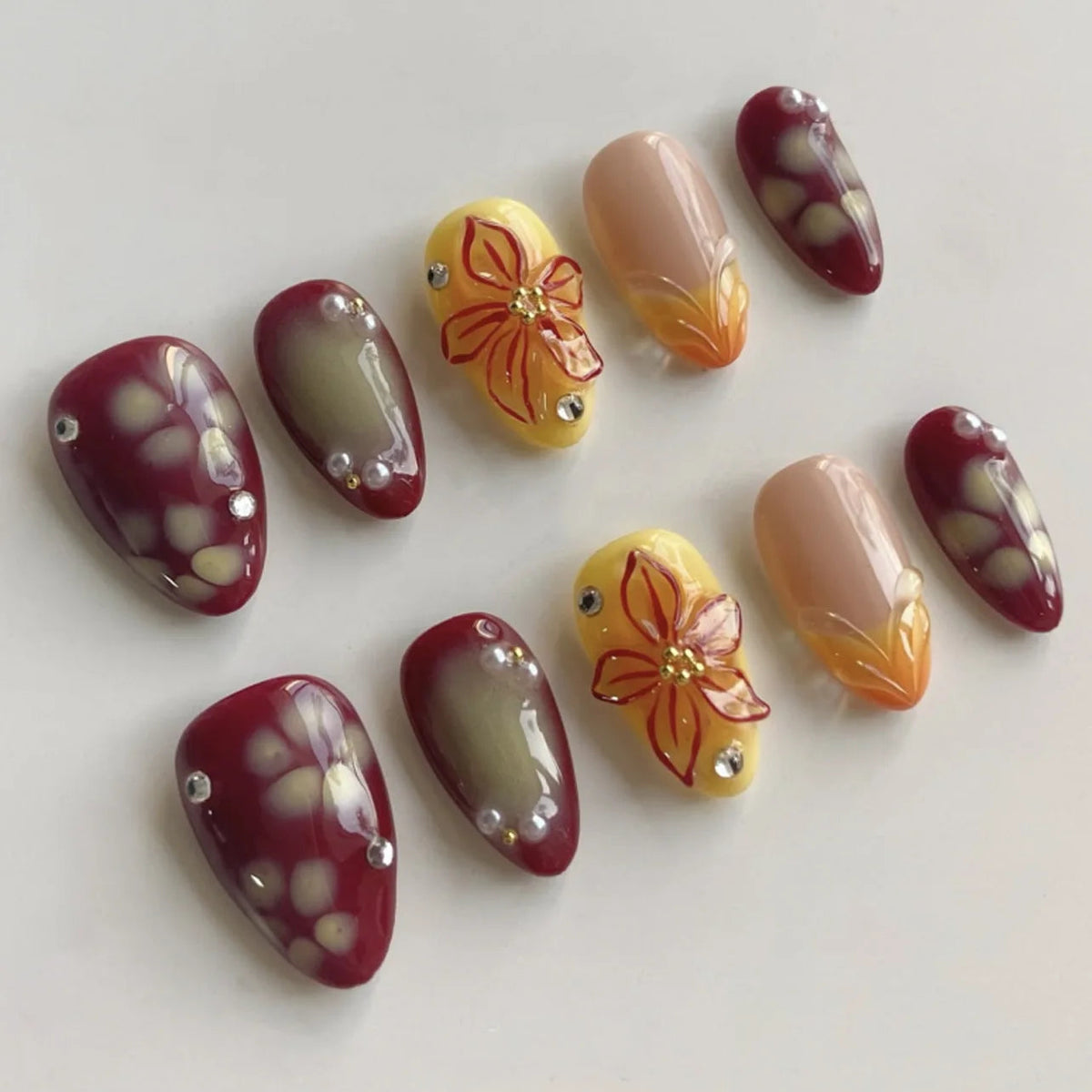 Glossy Burgundy Floral Nails with Orange Petals and Rhinestones