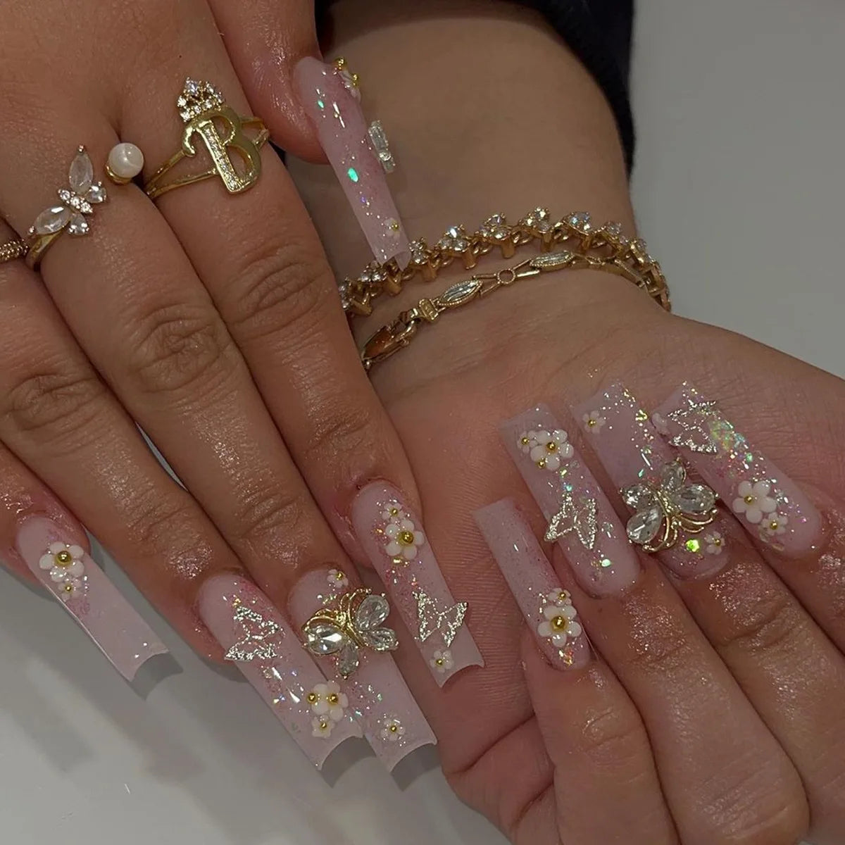 Nude Pink Floral Nails With Rhinestones, Gold Charms, and Glitter