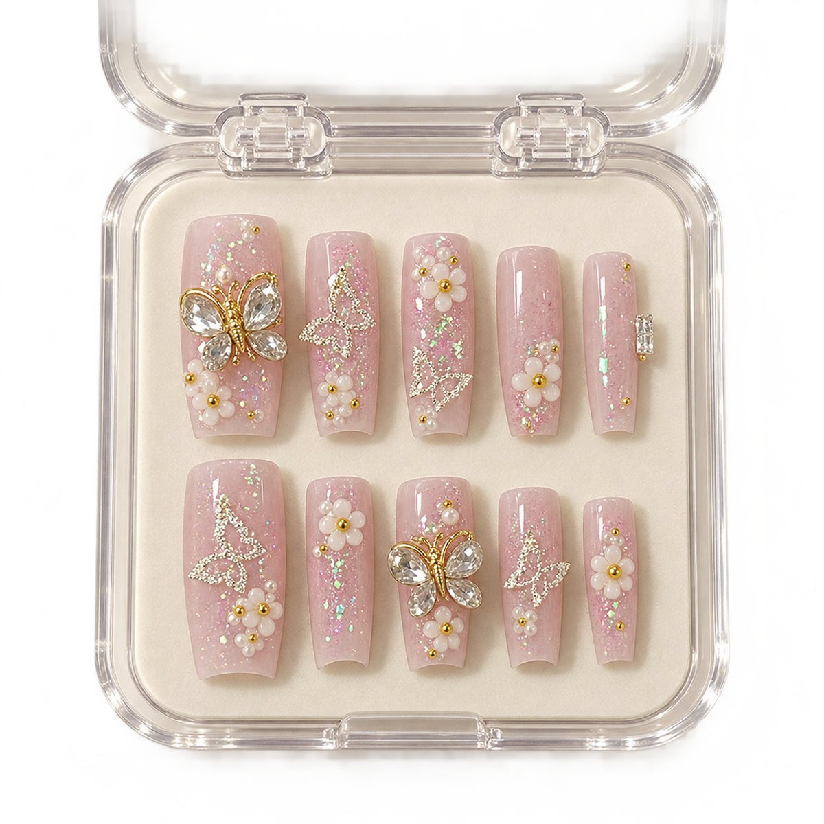 Nude Pink Floral Nails With Rhinestones, Gold Charms, and Glitter in clear acrylic storage box