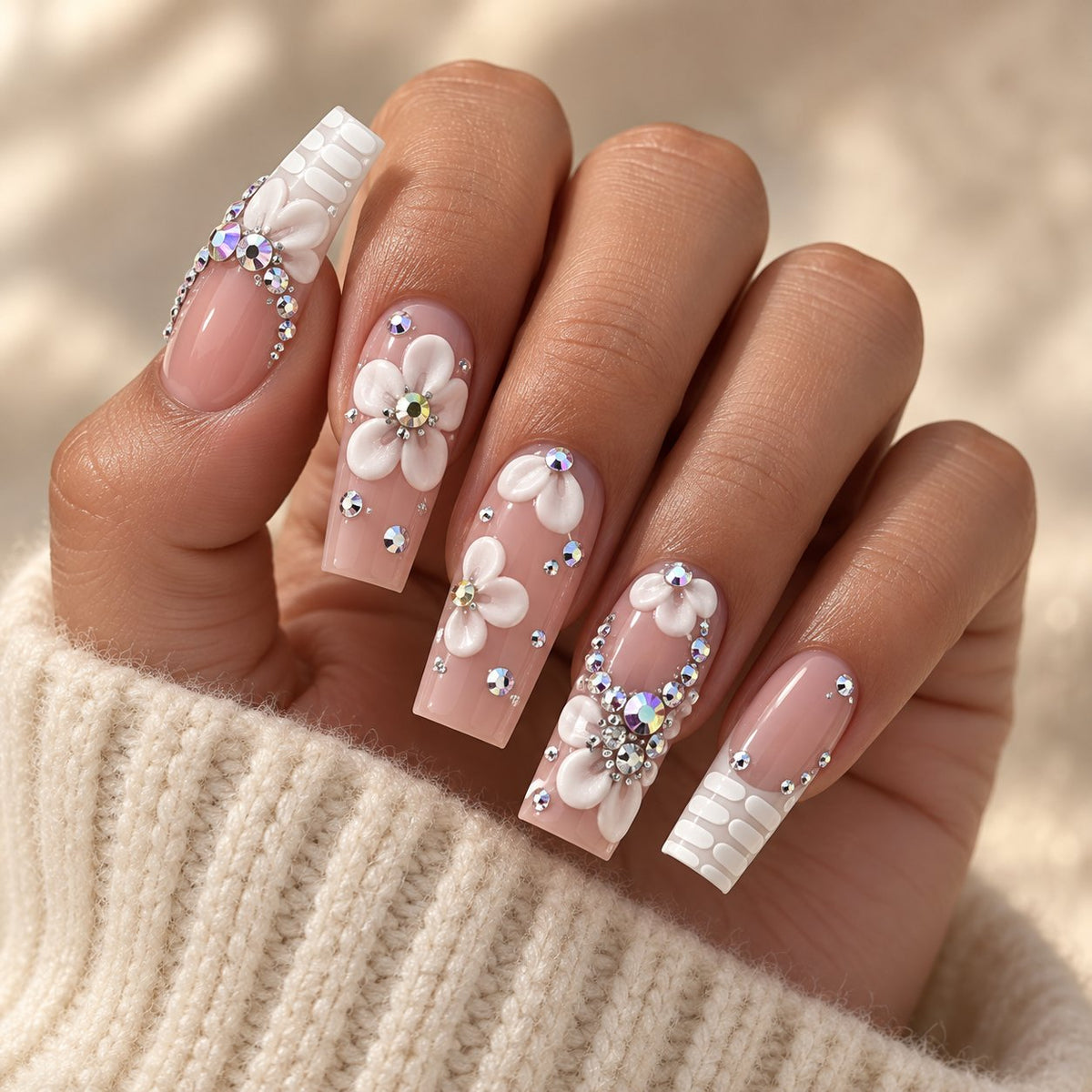 Nude Pink French Tip Nails With 3D White Flowers and Rhinestones worn on hand