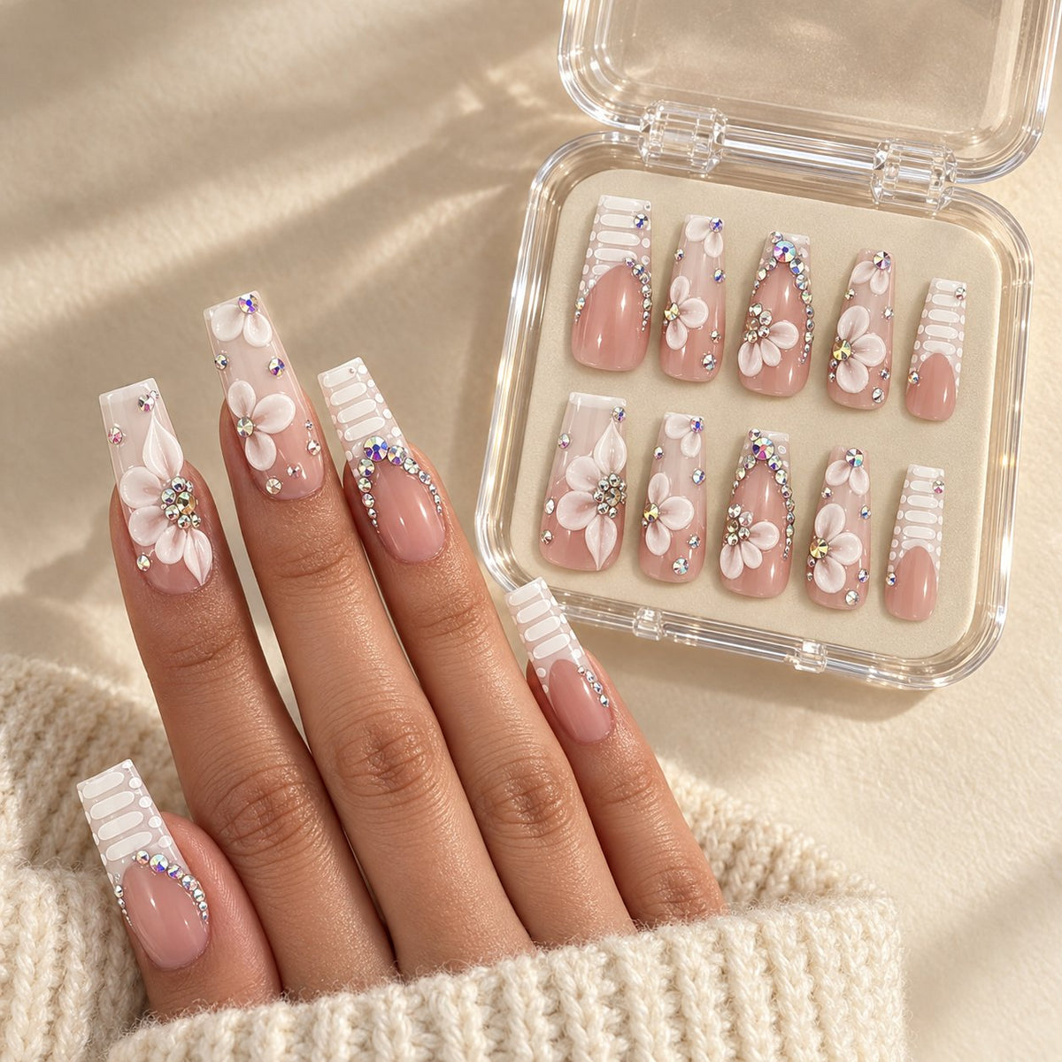 Nude Pink French Tip Nails With 3D White Flowers and Rhinestones worn on hand with acrylic storage box