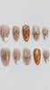 Blush French Tip Nails With Amber Dots, Gold Sun Motifs, and Rhinestones