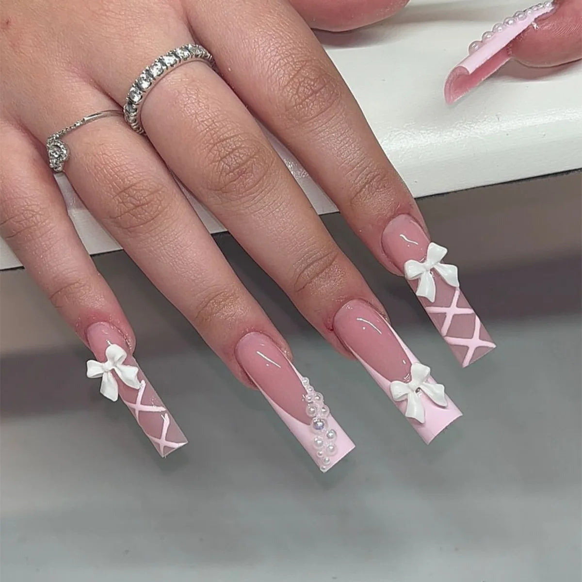 Sheer Pink French Tip Nails With White Bows and Pearl Accents